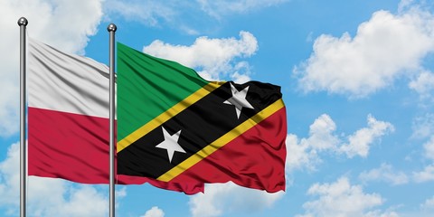 Poland and Saint Kitts And Nevis flag waving in the wind against white cloudy blue sky together. Diplomacy concept, international relations.