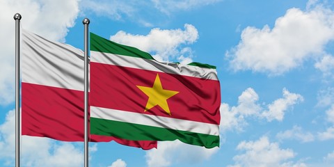 Poland and Suriname flag waving in the wind against white cloudy blue sky together. Diplomacy...