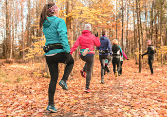 woman group out running together in an autumn park they run a race or train in a healthy outdoors lifestyle concept