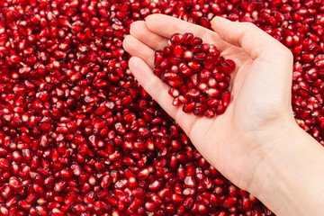 Red juicy pomegranate seeds in woman hand.