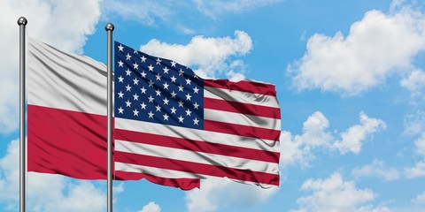 Poland and United States flag waving in the wind against white cloudy blue sky together. Diplomacy...