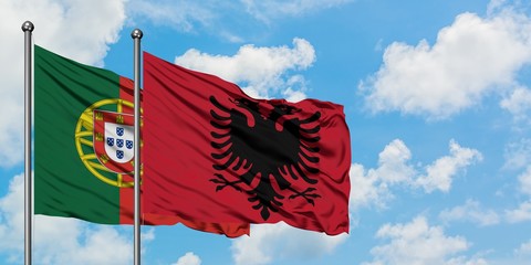 Portugal and Albania flag waving in the wind against white cloudy blue sky together. Diplomacy...