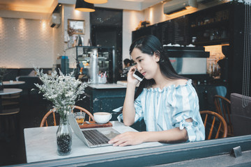 Asian woman with cell telephone in coffee shop.