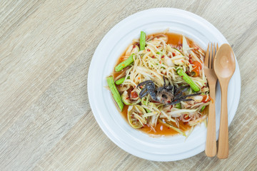 Green Papaya Salad (Som tum) is spicy on wood table