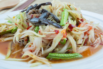 Green Papaya Salad (Som tum) is spicy on wood table