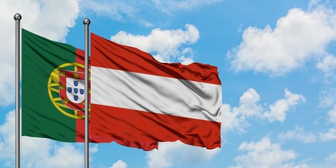 Portugal and Austria flag waving in the wind against white cloudy blue sky together. Diplomacy concept, international relations.