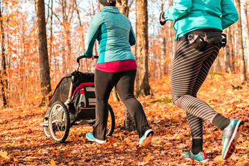Stroller woman group out running together in an autumn park they run a race or train in a healthy...