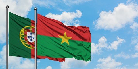 Portugal and Burkina Faso flag waving in the wind against white cloudy blue sky together. Diplomacy...