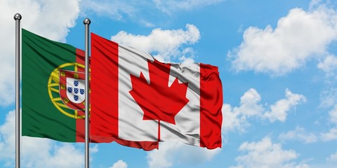 Portugal and Canada flag waving in the wind against white cloudy blue sky together. Diplomacy...