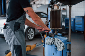 Modern station. Male mechanic use special device to repair broken automobile in garage