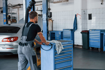 Car service. Male mechanic use different tools to repair broken automobile in garage