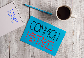 Writing note showing Common Mistakes. Business concept for actions that are often used interchangeably with error Stationary placed next to a cup of black coffee above the wooden table
