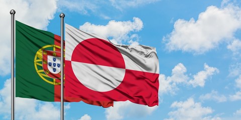 Portugal and Greenland flag waving in the wind against white cloudy blue sky together. Diplomacy...