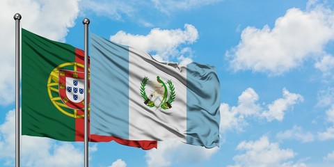 Portugal and Guatemala flag waving in the wind against white cloudy blue sky together. Diplomacy...