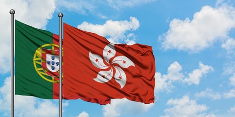 Portugal and Hong Kong flag waving in the wind against white cloudy blue sky together. Diplomacy...