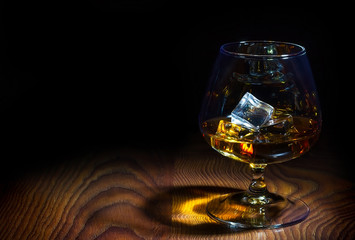 Glass of cognac with ice cubes