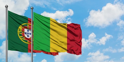 Portugal and Mali flag waving in the wind against white cloudy blue sky together. Diplomacy...