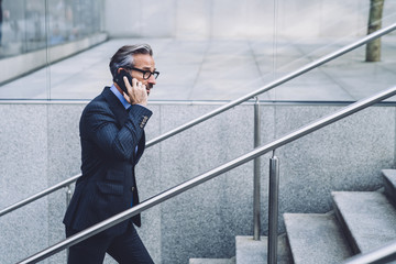 Middle-aged businessman talking by smartphone on urban background