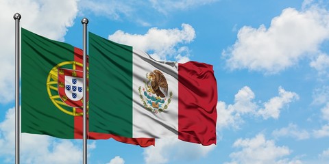 Portugal and Mexico flag waving in the wind against white cloudy blue sky together. Diplomacy...