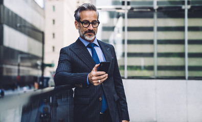 Middle-aged handsome man using smartphone on urban background