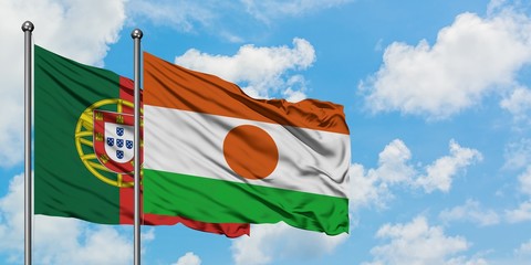 Portugal and Niger flag waving in the wind against white cloudy blue sky together. Diplomacy...