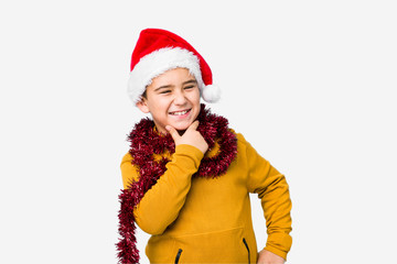 Little boy celebrating christmas day wearing a santa hat isolated looking sideways with doubtful and skeptical expression.