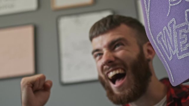 Cheerful bearded male fan rejoices and screaming while watching sport at apartment