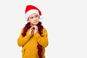 Little boy celebrating christmas day wearing a santa hat isolated making up plan in mind, setting up an idea.