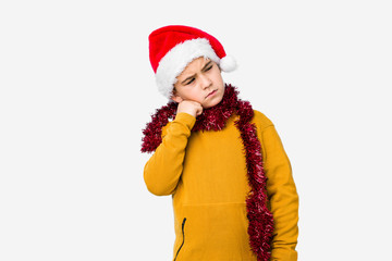 Little boy celebrating christmas day wearing a santa hat isolated who feels sad and pensive, looking at copy space.