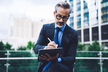 Adult male in business suit using tablet with stylus