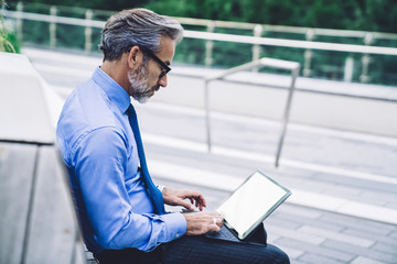 Businessman typing on keyboard with tablet while sitting on bench in New York