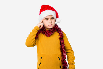 Little boy celebrating christmas day wearing a santa hat isolated pointing temple with finger, thinking, focused on a task.