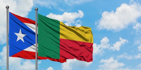 Puerto Rico and Benin flag waving in the wind against white cloudy blue sky together. Diplomacy concept, international relations.
