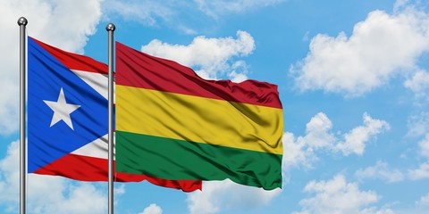 Puerto Rico and Bolivia flag waving in the wind against white cloudy blue sky together. Diplomacy concept, international relations.