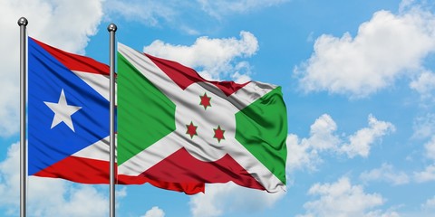 Puerto Rico and Burundi flag waving in the wind against white cloudy blue sky together. Diplomacy concept, international relations.