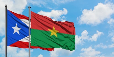 Puerto Rico and Burkina Faso flag waving in the wind against white cloudy blue sky together. Diplomacy concept, international relations.