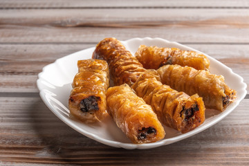 Traditional greek pastries saragli in a white plate on a wooden background