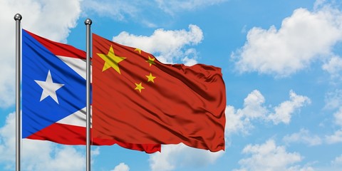 Puerto Rico and China flag waving in the wind against white cloudy blue sky together. Diplomacy concept, international relations.