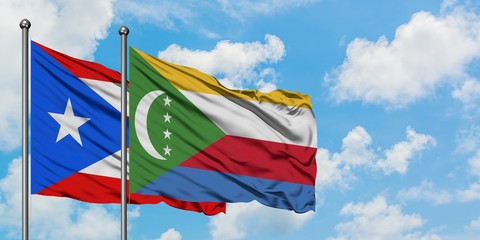 Puerto Rico and Comoros flag waving in the wind against white cloudy blue sky together. Diplomacy...