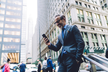 Laughing businessman with smartphone in city street