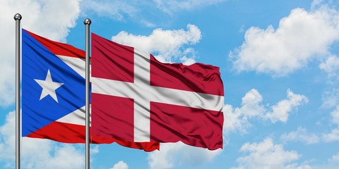 Puerto Rico and Denmark flag waving in the wind against white cloudy blue sky together. Diplomacy...