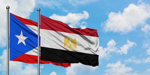 Puerto Rico and Egypt flag waving in the wind against white cloudy blue sky together. Diplomacy concept, international relations.