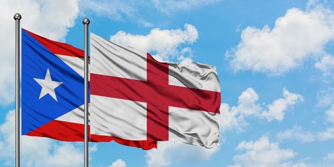 Puerto Rico and England flag waving in the wind against white cloudy blue sky together. Diplomacy concept, international relations.