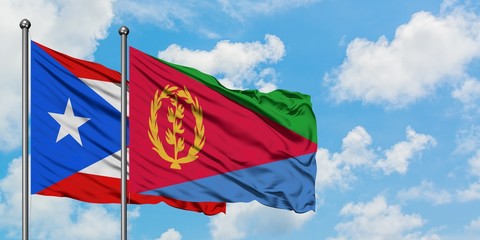 Puerto Rico and Eritrea flag waving in the wind against white cloudy blue sky together. Diplomacy concept, international relations.