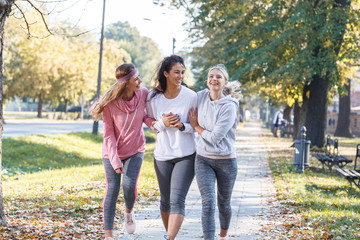 Group of female friends jogging at the city park.Relaxing after running and making fun.Autumn...