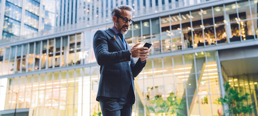 Middle aged elegant male looking at mobile outdoors