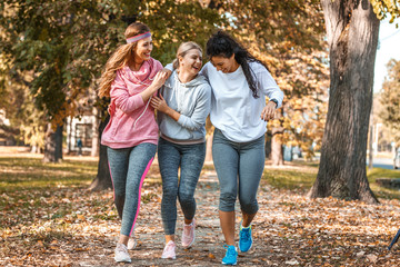 Group of female friends jogging at the city park.Relaxing after running and making fun.Autumn...