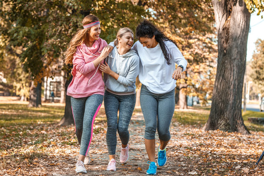 Group of female friends jogging at the city park.Relaxing after running and making fun.Autumn season.	