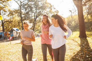 Group of female friends jogging at the city park in the morning.Autumn season
