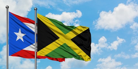 Puerto Rico and Jamaica flag waving in the wind against white cloudy blue sky together. Diplomacy concept, international relations.